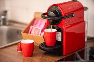 een rood koffiezetapparaat met twee rode kopjes op een aanrecht bij DUOMO - Prestigious Penthouse with Panoramic View in Milaan