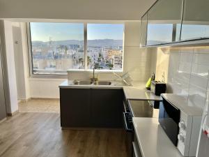 a kitchen with a sink and a large window at Seaview Beach Apartment Dasoudi in Limassol