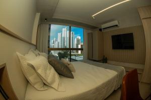 a bedroom with a bed with a view of a city at BOA VIAGEM - FLAT ROOFTOP ALTO PADRÃO in Recife