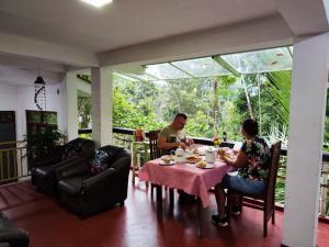 a man and woman sitting at a table on a porch at AnandaHomestay in Kandy
