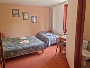 a hotel room with two beds and a table and a toilet at Au Pont de la Ginéze in Barjac