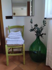 Un jarrón verde con flores al lado de una silla en Contrada Macchia B&B, en Tricase