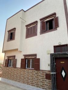 un bâtiment avec des fenêtres à volets marron et une porte dans l'établissement Panorama guest house, à Sidi Ifni