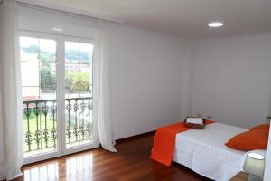 een slaapkamer met een bed en een groot raam bij Apartamento Carrera in Caldas de Reis