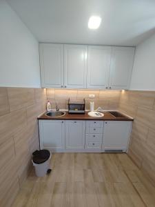 una pequeña cocina con armarios blancos y fregadero en Apartments Marjanović, en Zlatibor