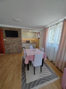 a dining room with a pink table and a kitchen at Apartments Marjanović in Zlatibor
