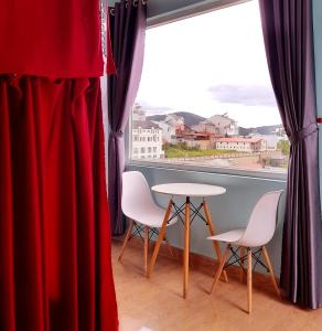 a room with a table and two chairs and a window at Hugo's Family in Da Lat