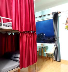 Hugo's Family في دالات: غرفة نوم مع سرير بطابقين مع ستائر حمراء وطاولة
