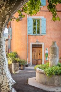 an orange building with a wooden door in front of it at Des Lits Sur La Place in Hérépian