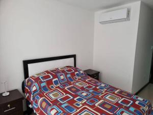 a bed with a colorful comforter in a bedroom at Santa Cruz Hermoso Departamento Piscina Toboganes in Santa Cruz de la Sierra