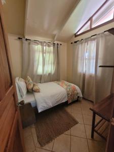 a small bedroom with a bed and a window at Cabina Rancho la Merced in Uvita