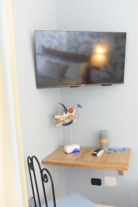 ein kleines Holzregal an einer Wand mit einem TV in der Unterkunft Villa Elicriso in Carloforte