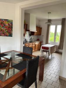 cocina y comedor con mesa de cristal y sillas en Maison 90 m2 (Logement complet), en Miraumont