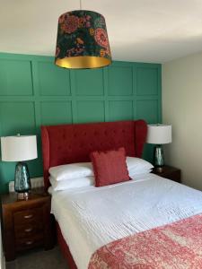 ein Schlafzimmer mit einem Bett mit einem roten Kopfteil und zwei Lampen in der Unterkunft Overdale Motel in Lisburn