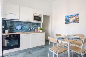 une cuisine avec des armoires blanches et une table avec des chaises dans l'établissement La Casa degli Oleandri, à Torre Santa Sabina