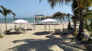 a beach with chairs and umbrellas and the ocean at Hospedaje "Las Brisas de Zorritos" in Zorritos