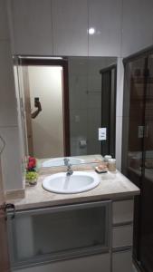 um balcão de casa de banho com um lavatório e um espelho em Condominio Chateau Mondrian em Cabo Frio