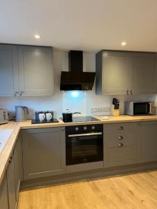 uma cozinha com armários cinzentos e um forno com placa de fogão em Beautiful mid wales cottage em Garth