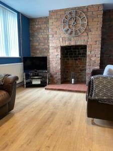 a living room with a brick fireplace with a tv at Beautiful mid wales cottage in Garth
