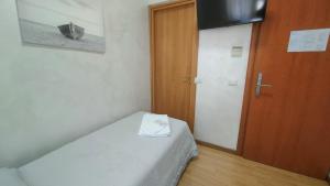 Kleines Zimmer mit einem Bett und einer Holztür in der Unterkunft Hotel Eriale in Rimini