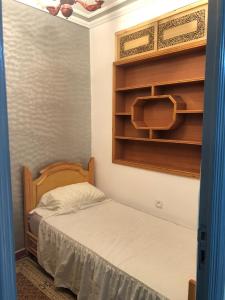 a small bedroom with a bed and wooden shelves at Casa Del Flor in Larache