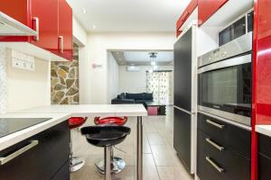 a kitchen with red cabinets and a counter with stools at Άνετο & ήσυχο διαμέρισμα για 4 in Athens