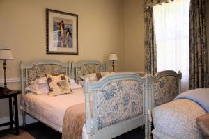 een slaapkamer met 2 bedden en een raam met gordijnen bij Hacklewood Hill Country House in Port Elizabeth