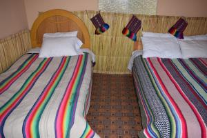 two beds sitting next to each other in a room at Taquile Sumaq Wasi - Casa de Felipe e Ines in Huillanopampa