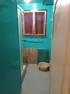 uma casa de banho azul com um WC e uma janela em Maison complète em Montluçon