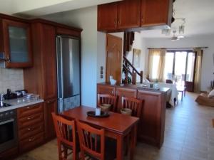 a kitchen with wooden cabinets and a table with chairs at κτήμα ΝΟΣΤΟΣ in Aigio
