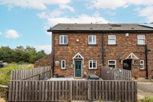 a brick house with a wooden fence in front of it at Canal Side Cottage Wakefield in Stanley
