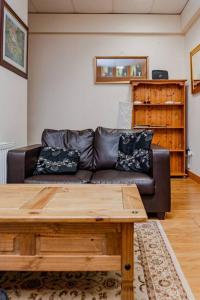 a living room with a leather couch and a wooden table at 2 Bed on The Main Street in Clogherhead