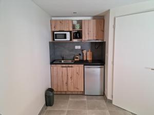 a small kitchen with wooden cabinets and a microwave at Studio Gîtes Au Pont de la Ginéze in Barjac