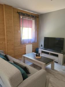 sala de estar con sofá y TV de pantalla plana en La ferme du Badon, en Gérardmer