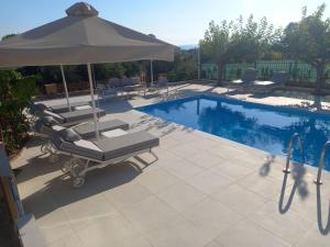 a swimming pool with two lounge chairs and an umbrella at Villa Evàlia - Private Villa With Pool -Malakonda ,Eretria ,Greece in Eretria