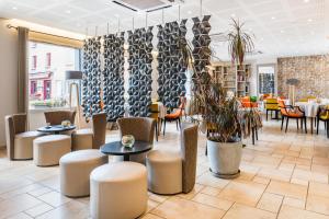 a restaurant with tables and chairs and plants at Le Place Neuve in Brullioles