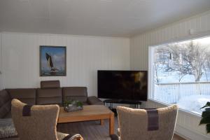 a living room with a couch and a flat screen tv at Captains House in Hamneide