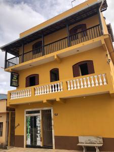 een geel huis met een balkon erboven bij Pousada Véu de Noiva in São Thomé das Letras
