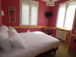 um quarto com uma cama branca, paredes vermelhas e janelas em Hôtel de France em Pont-lʼÉvêque