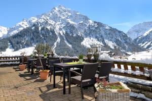 a patio with a table and chairs in front of a mountain at Hoheneck Apartment in Mittelberg