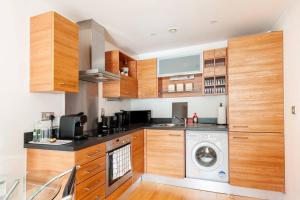 a kitchen with wooden cabinets and a washer and dryer at Cozy Apt Near Central Leeds in Hunslet
