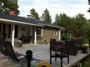 eine Terrasse mit Stühlen und ein Haus in der Unterkunft Cozy and Private 3-Bed House with bath Roslagen in Herräng