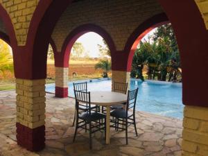 a table and chairs under an archway with a pool at Bambi Lodge in Groutfontein