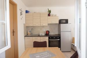 uma pequena cozinha com um frigorífico branco e uma mesa em Apartmani Skledar em Vodice