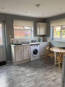 a kitchen with a washing machine and a table at The Bungalow in Dersingham