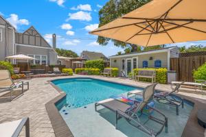 a swimming pool with two chairs and an umbrella at The Kenwood Gables in St. Petersburg
