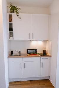a kitchen with white cabinets and a sink at Designoase für 3 mit Blick auf den Wismarer Hafen in Wismar