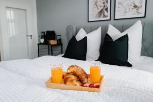 a tray of croissants and orange juice on a bed at Designoase für 3 mit Blick auf den Wismarer Hafen in Wismar