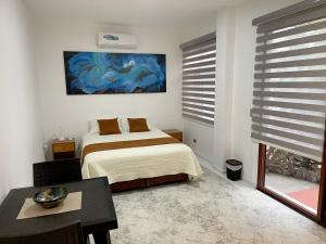 1 dormitorio con cama, mesa y ventana en Maytenus Galapagos, en Puerto Ayora