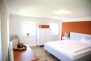 a bedroom with a bed and a desk and two windows at Ferienhaus Rabenbrunn in Arnstorf